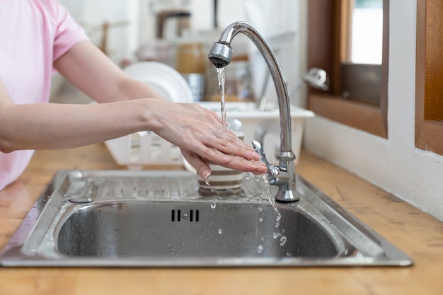 Mains d'une femme se lavant avec de l'eau propre dans la cuisine à la maison pendant la crise du coronavirus ou l'épidémie de covid-19.