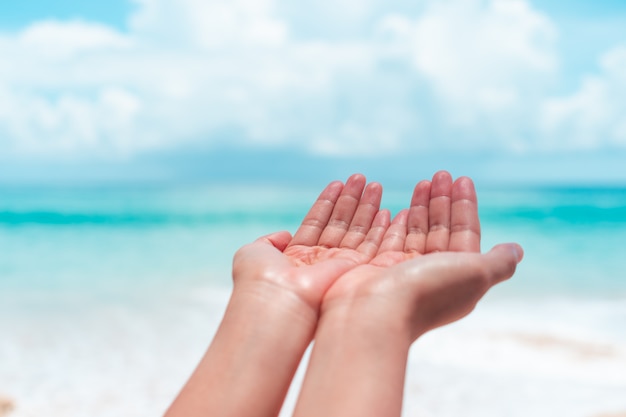 Les mains de la femme se placent ensemble comme prier devant la plage propre de la nature et le ciel bleu.