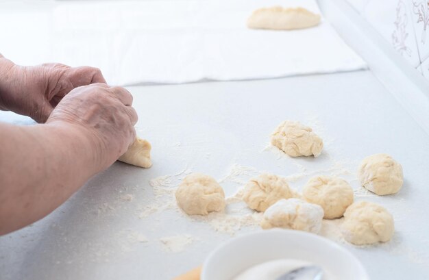 Mains de femme senior faisant des tartes aux pommes sur une table de cuisine blanche avec un rouleau à pâtisserie en bois sur fond Mise au point sélective Cuisine à la maison concept Cuisine traditionnelle faite maison