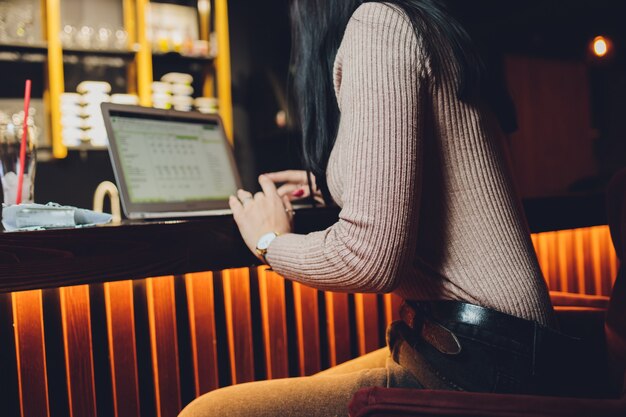 Mains de femme tapant sur ordinateur portable, tablette et vin rouge à l'extérieur dans le café.