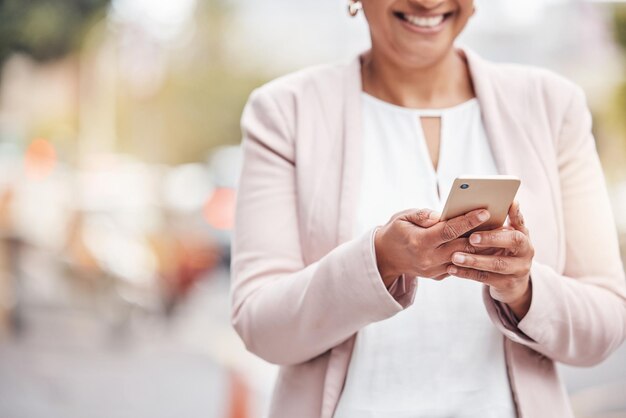 Mains de femme et téléphone en ville pour la communication sur les réseaux sociaux ou le chat et l'envoi de SMS