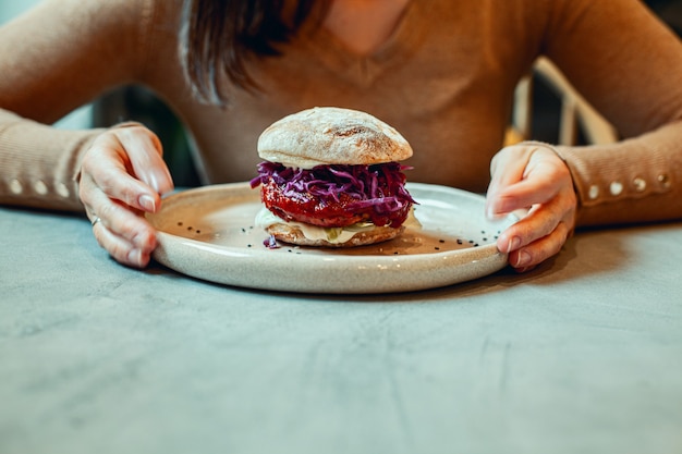 Photo mains de femme tenant une assiette de hamburger végétarien à la betterave