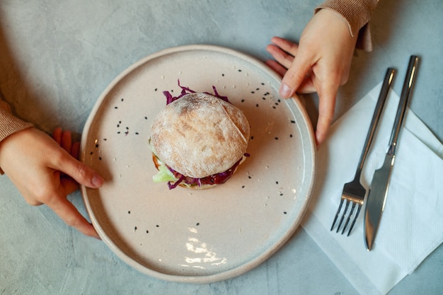 Mains de femme tenant une assiette de hamburger végétarien à la betterave