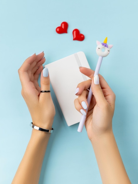 Mains de femme tenant un bloc-notes sur une table bleue Accessoires d'été féminins