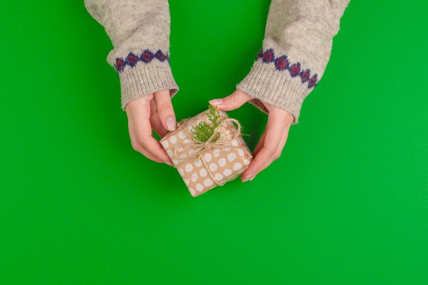 Mains de femme tenant une boîte-cadeau sur fond vert