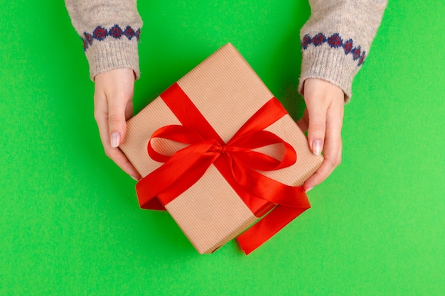 Mains de femme tenant une boîte-cadeau sur fond vert