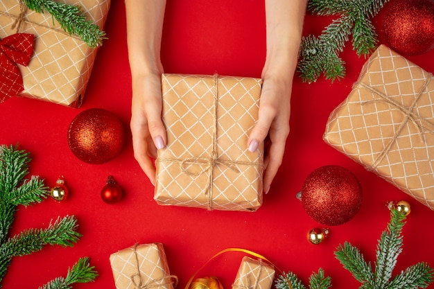 Mains de femme tenant une boîte de cadeau de Noël sur fond rouge