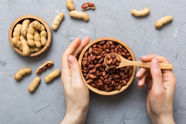 Mains de femme tenant un bol en bois avec des cacahuètes Aliments sains et collations Collations végétariennes de différentes noix