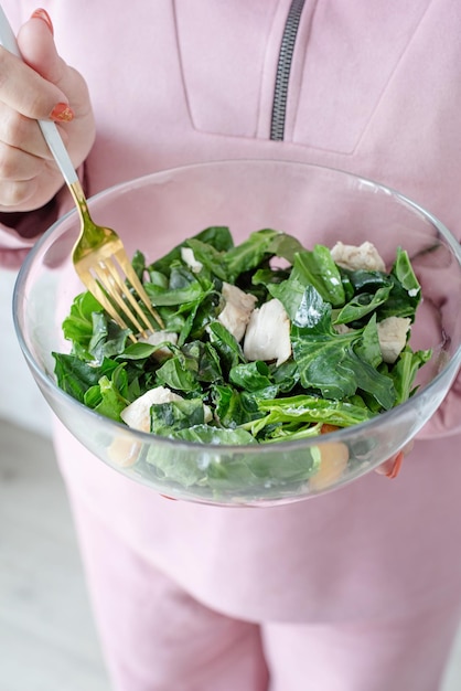 Mains de femme tenant un bol de salade saine aux épinards et à la pêche