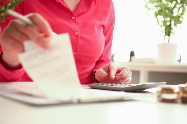 Mains de femme tenant une calculatrice et un chèque payé en gros plan