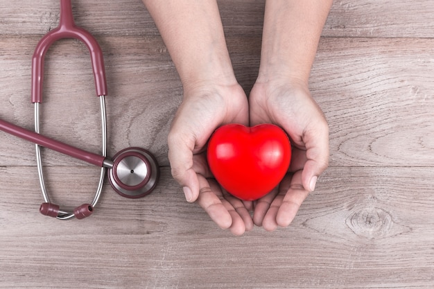 Mains de femme tenant coeur rouge et stéthoscope