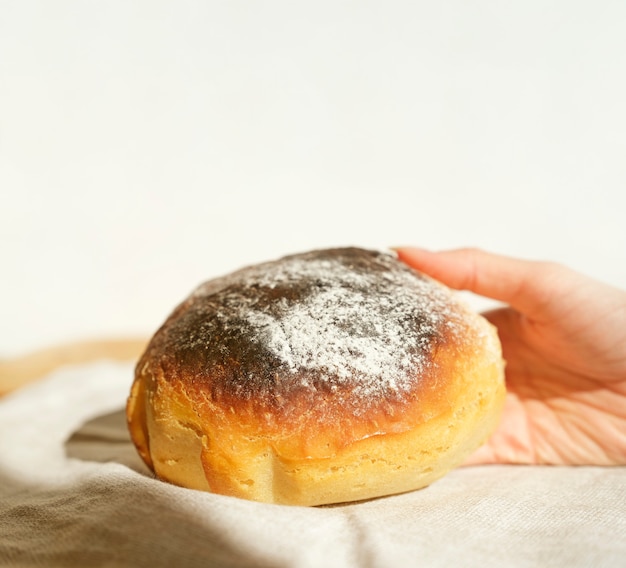 Mains d'une femme tenant du pain frais à la maison se bouchent. Fond blanc.