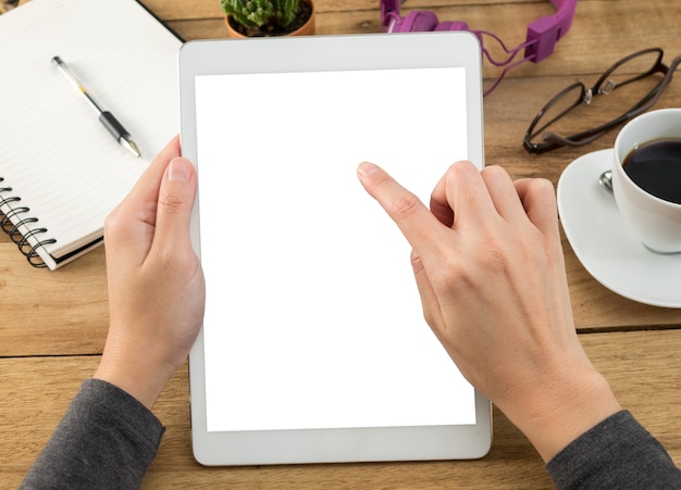 mains de femme tenant un écran vide de tablette sur le travail de bureau en bois.