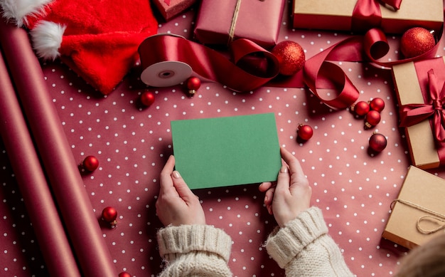 Mains de femme tenant une enveloppe verte sur du papier d'emballage