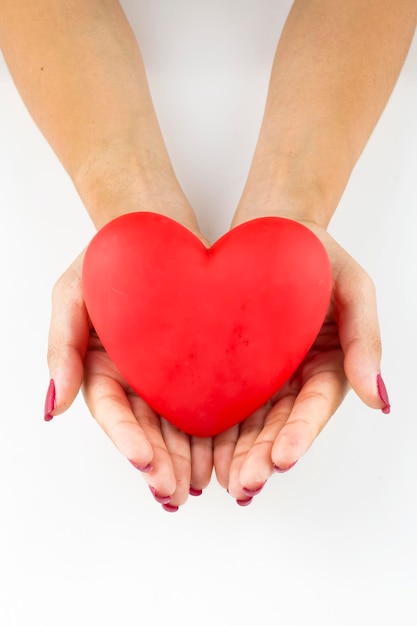 Mains de femme tenant la figure du coeur en rouge