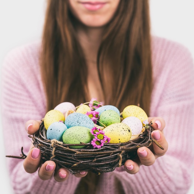 Mains de femme tenant un oeuf de pâques peint dans un petit nid photo aux tons mise au point sélective