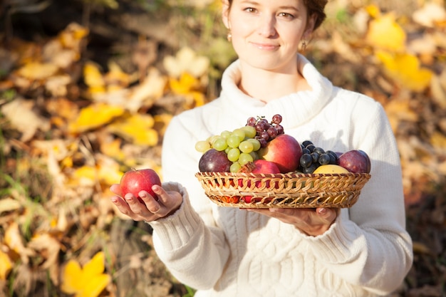 Mains de femme tenant un panier avec des fruits frais. Fermer