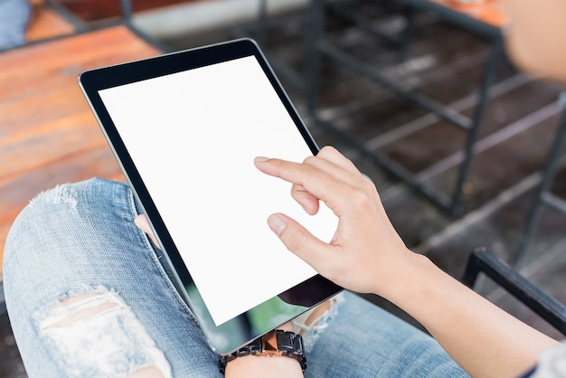 Mains de femme tenant et pointant sur cadre numérique contemporain avec écran blanc.