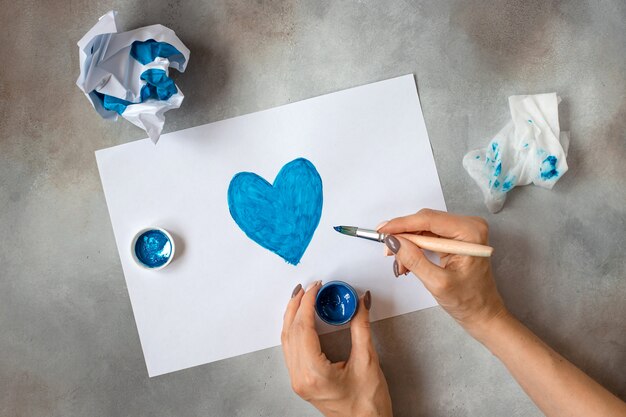 Mains de femme tenant un pot avec de la peinture bleue et dessine une image. créativité, peinture