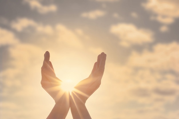 Mains de femme tenant le soleil à l'aube