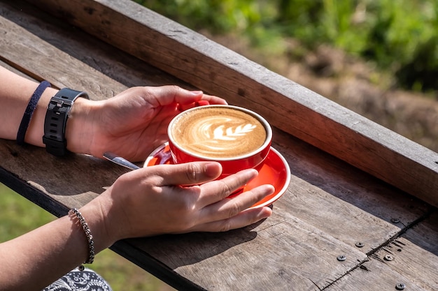 Mains de femme tenant une tasse d'art de café orange