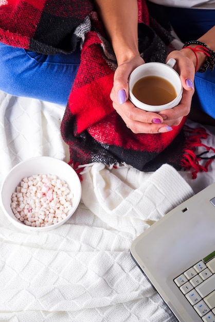 Mains D'une Femme Tenant Une Tasse De Café Chaud Au Lit Avec Un Plaid