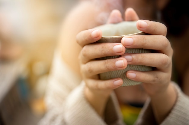 Mains de femme tenant une tasse de café.