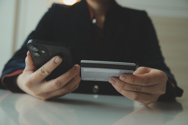 Mains de femme tenant et utilisant une carte de crédit pour faire des achats en ligne