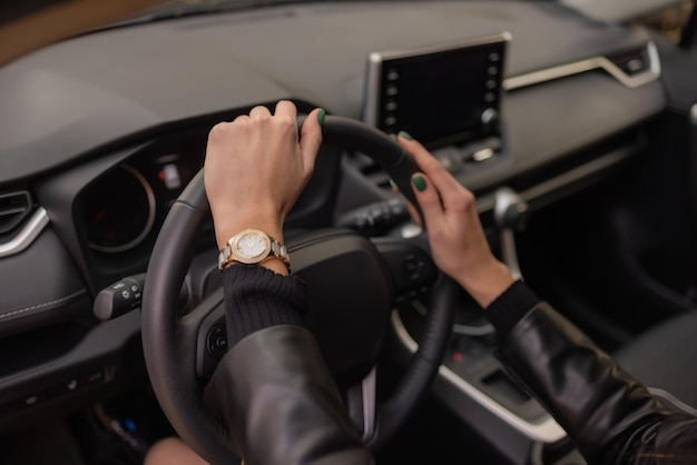 Mains de femme tenant le volant d'une nouvelle voiture dans la salle d'exposition.