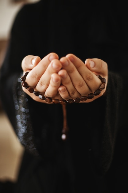 Les mains de la femme tiennent le chapelet pendant la prière