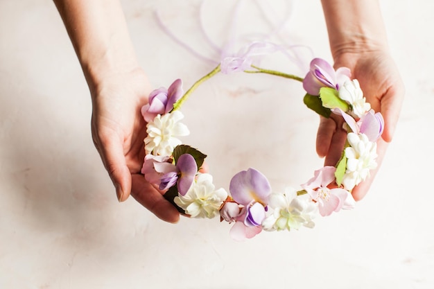 Les mains de la femme tiennent une couronne de mousse avec des fleurs de sprint. Accessoire de mode pour la coiffure