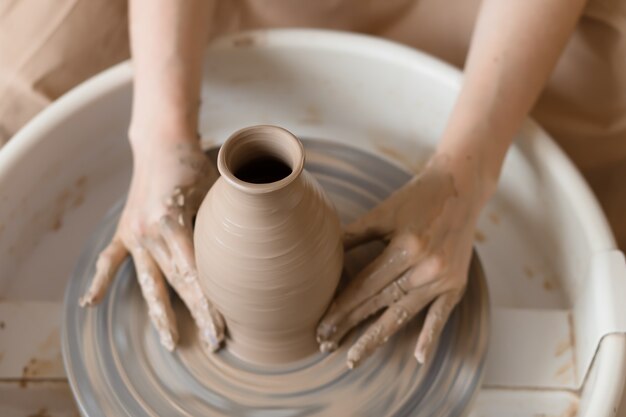 Mains de femme travaillant avec de l'argile et un tour de poterie