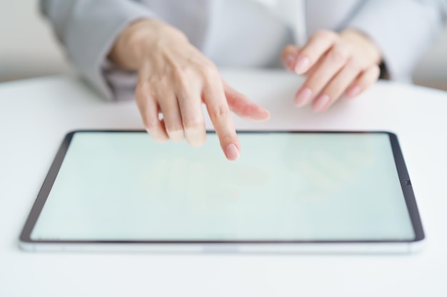 Mains d'une femme utilisant une tablette PC à l'intérieur