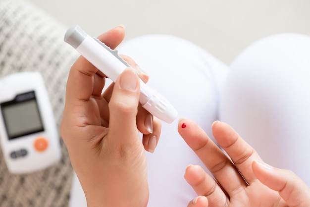 Mains de femme vérifiant le niveau de sucre dans le sang par glucomètre pour testeur de diabète