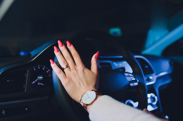 Mains de femme sur le volant au volant d'une voiture de luxe moderne. Concept femme au volant. Mains tenant le volant pendant la conduite. Voiture à l'intérieur. Détails de voiture.