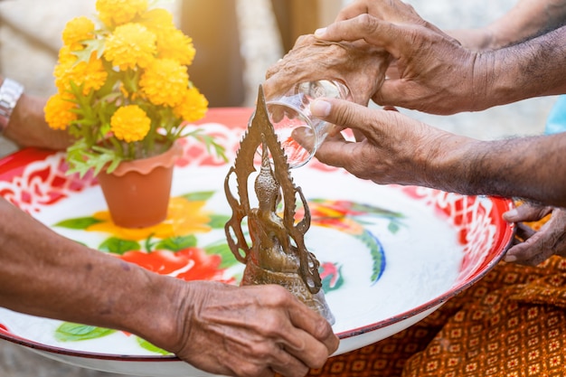 Des mains de femmes âgées versant de l&#39;eau sur la statue de Bouddha est le jour de Songkran