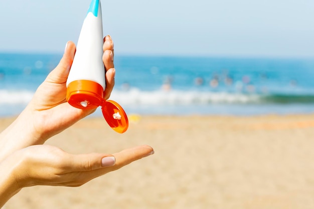 Les mains des femmes appliquent un écran solaire sur la plage. Concept de protection contre les bains de soleil.