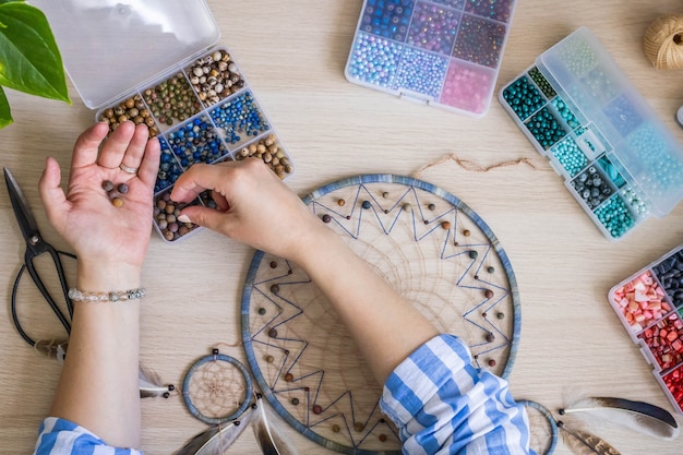 Les mains des femmes artistiques utilisent des perles colorées pour créer un capteur de rêves amulette indien tribal indigène