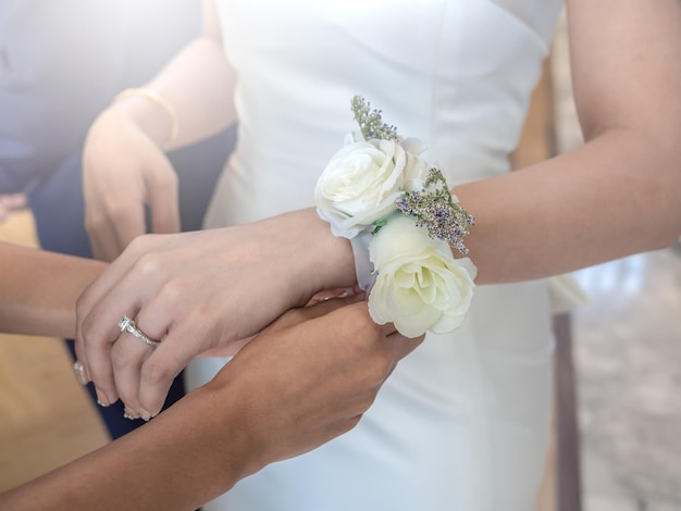 Mains de femmes attachant le bracelet de fleur de rose blanche à la mariée