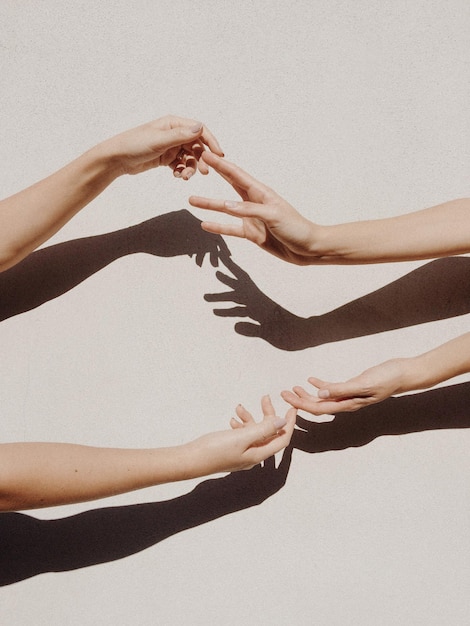 Photo des mains de femmes coupées contre un mur gris.