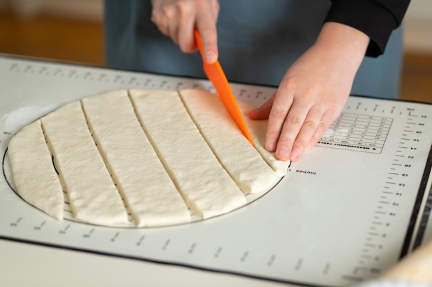 Les mains des femmes coupent la pâte pour les baursaks Cuisson des pâtisseries d'Asie centrale