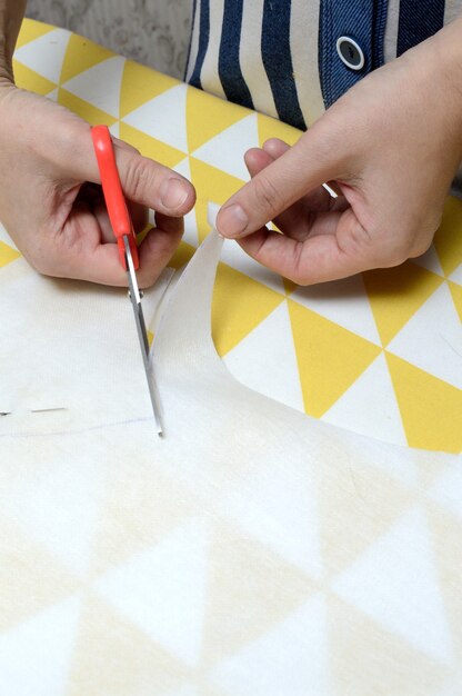 Les mains des femmes coupent le tissu avec des ciseaux selon le motif sur la table.