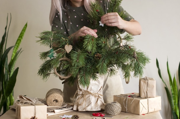 Les mains des femmes décorent des branches de conifères avec des ornements en matériaux naturels