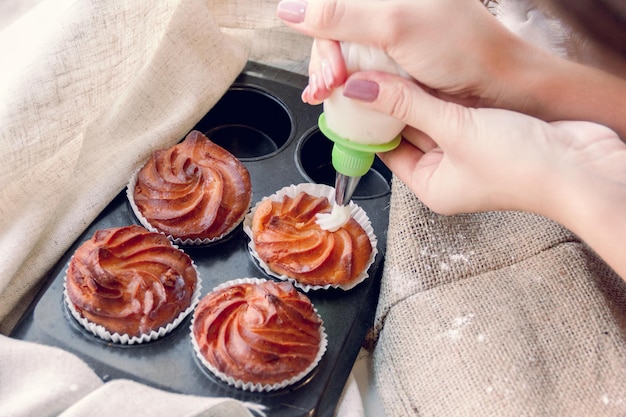 Les mains des femmes décorent des cupcakes avec de la crème