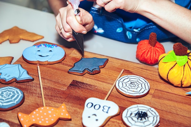 Les mains des femmes décorent le pain d'épice comme un doux cadeau d'Halloween pour les enfants