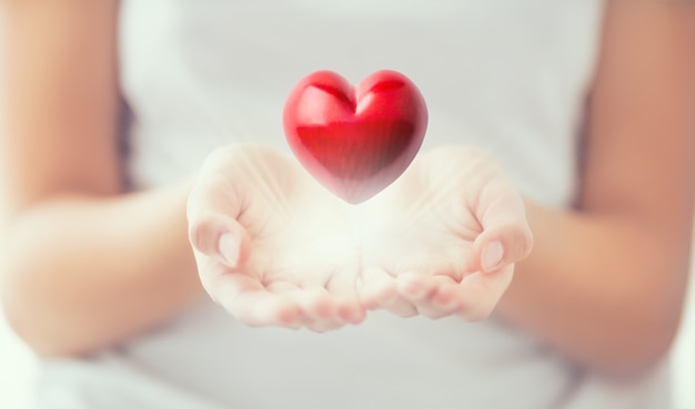 Des mains de femmes douces et un coeur rouge brillant dans ses mains. Saint Valentin fête des mères et concept de charité.