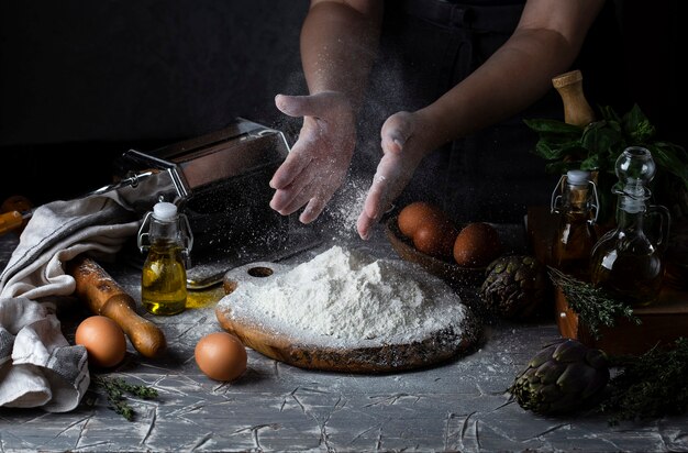 Les mains des femmes faisant des pâtes de style rustique foncé