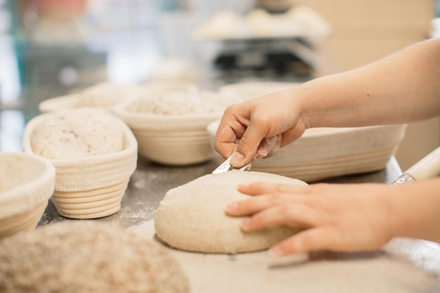 Les mains des femmes font une incision sur une pâte ronde avant de faire du painxA