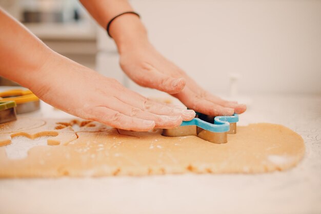 Les mains des femmes forment des moules avec de la pâte au gingembre et font de délicieux biscuits de Noël au gingembre. Cuisiner et décorer le dessert de Noël.