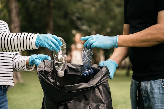 Les mains des femmes et des hommes collectent les déchets plastiques pour les nettoyer dans le parc